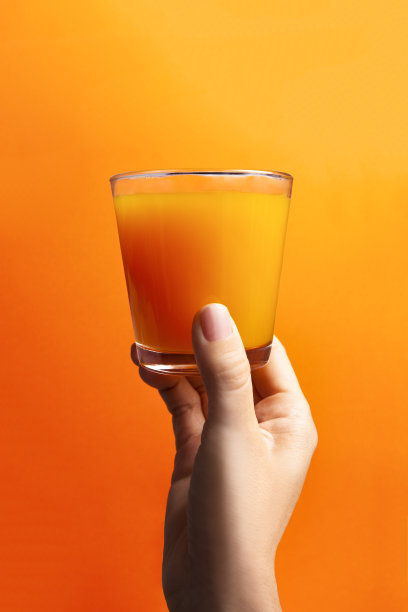 拿着一杯橙汁在橙色的背景图片下载