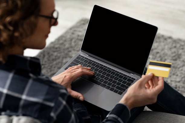 男人使用笔记本电脑和信用卡在网上购物室内，后视图图片下载