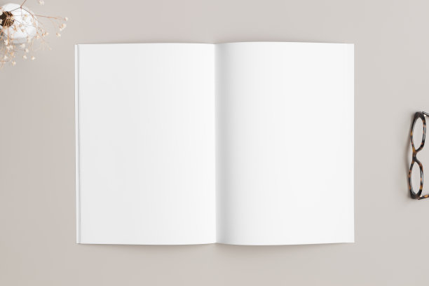 打开杂志模型，米色的桌子上放着玻璃杯和茄菲鱼。图片下载