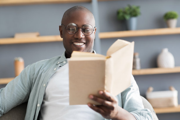 休闲的概念。黑人成熟男人读书，享受长篇小说畅销小说，有选择的焦点图片下载
