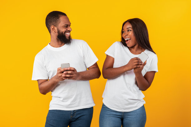 一对非洲裔美国夫妇在用手机，工作室墙上是黄色的图片下载