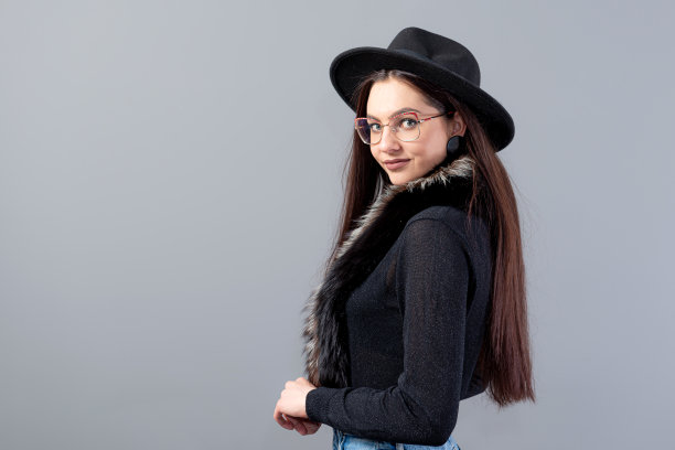 一个性感的女人的肖像与长头发和黑色的帽子在她的头孤立在一个灰色的背景图片下载