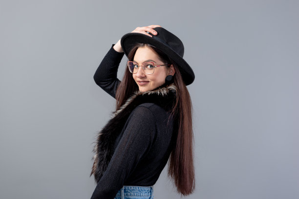 一个性感的女人的肖像与长头发和黑色的帽子在她的头孤立在一个灰色的背景图片下载