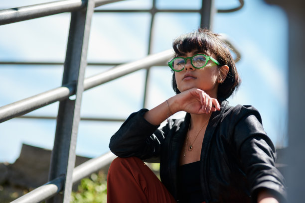 一个年轻女人戴着眼镜坐在外面的照片图片下载