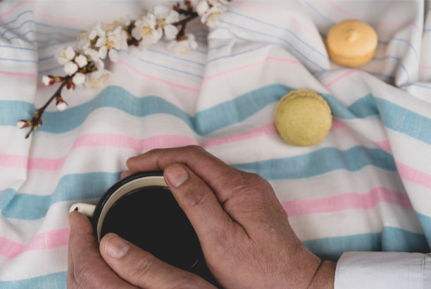 男人双手捧着一杯热咖啡躺在床上，俯视图。图片下载