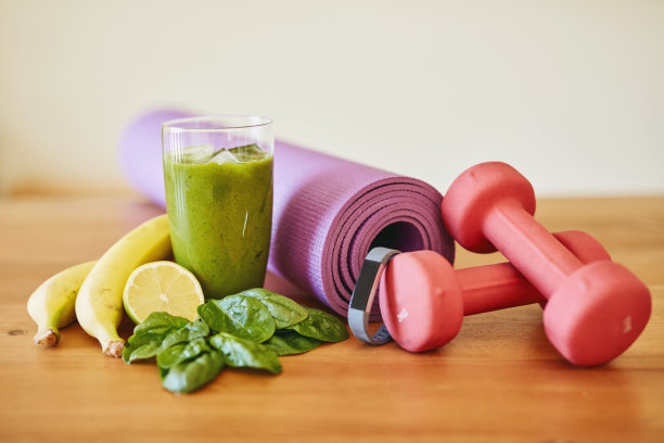 一个新鲜的绿色奶昔和健身设备在桌子上的特写镜头图片下载