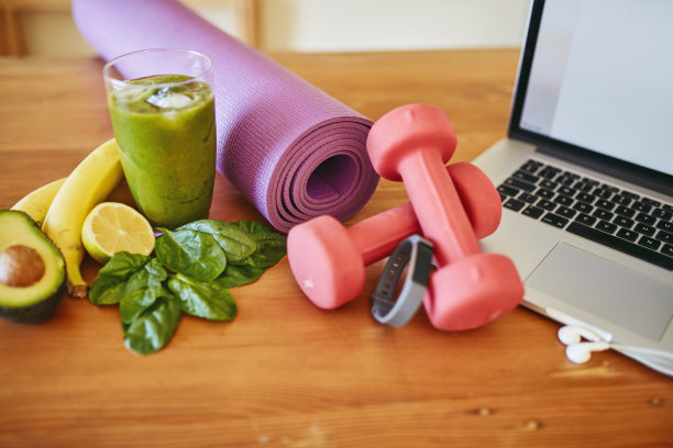 高角度拍摄新鲜的绿色奶昔，健身设备和桌上的笔记本电脑图片下载