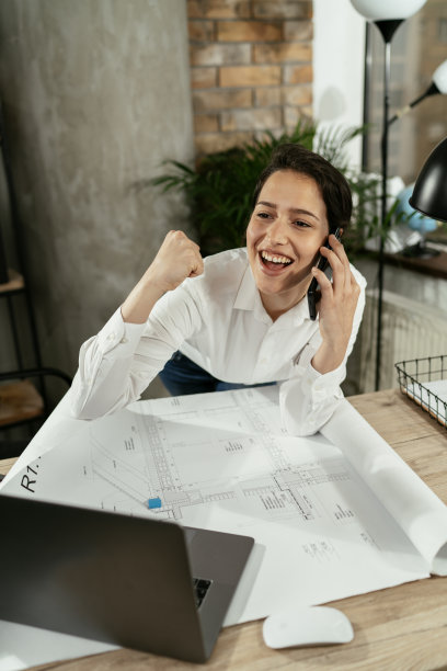 一个成功的年轻女性在办公室里打电话。库存图片图片下载