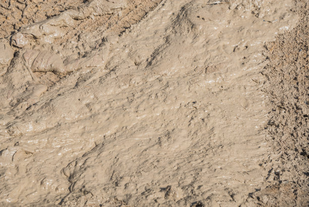 泥泞的道路上有车轮的痕迹。泥质地的背景。图片下载