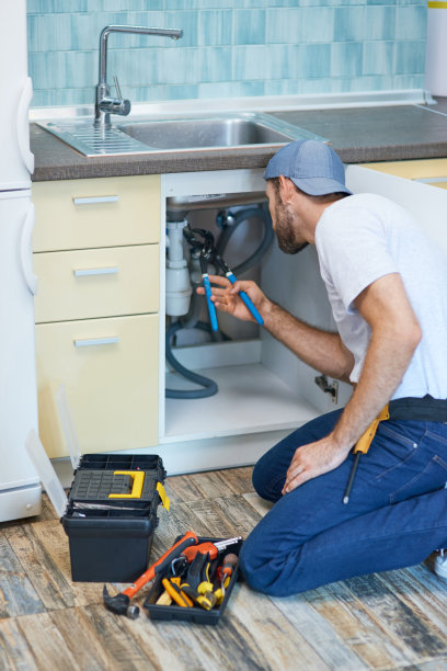 管道的麻烦。专业水管工在检查和修理厨房水槽时使用管钳图片下载