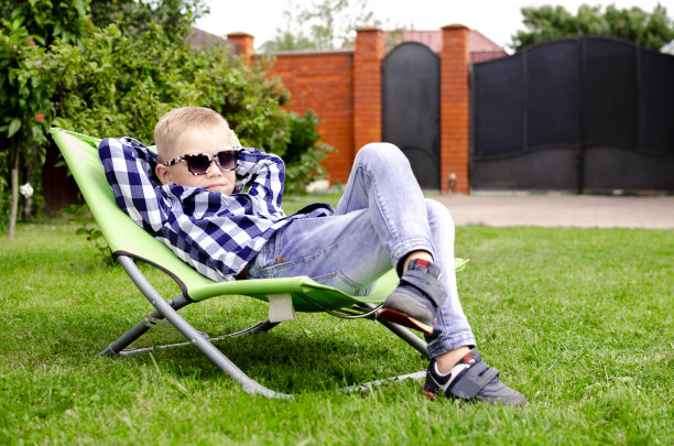 夏天，孩子们戴着太阳镜在太阳躺椅上晒太阳。家庭度假。假期在自然界中图片下载