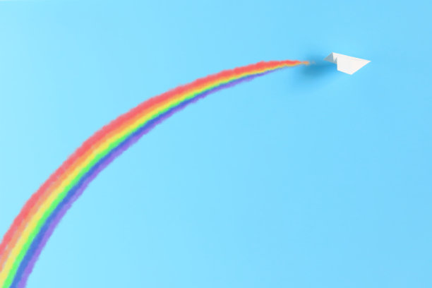 用尾迹画彩虹的纸飞机。图片下载