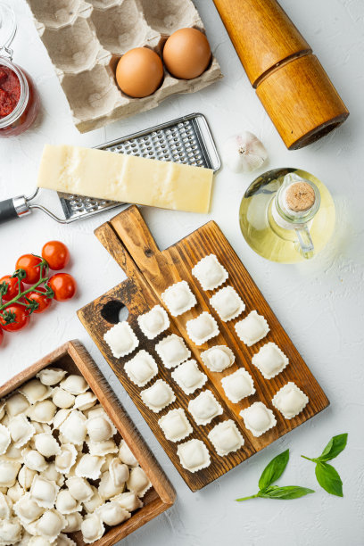 生意大利饺子，新鲜的帕尔马干酪和罗勒，西红柿在木板上，白色背景，俯视图平铺图片下载