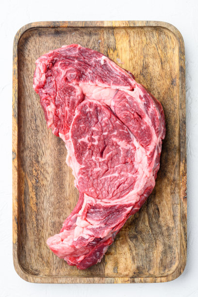 生肋眼牛排大理石般的肉与盐，迷迭香和大蒜，在白色的石头背景，俯视图平lay图片下载