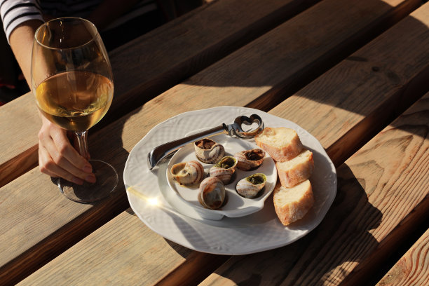 女孩坐在户外咖啡馆享受蜗牛与香草，黄油和白葡萄酒图片下载