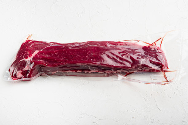 新鲜生牛肉真空包装菲力牛排切，在白色的石头背景图片下载