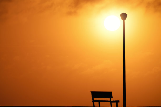 木凳和街灯，背景是夕阳和灿烂的太阳。图片下载