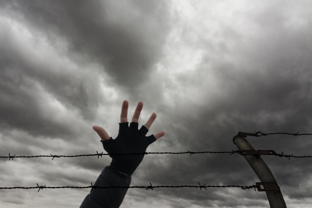 一个在铁丝网后面的男人张开的手图片下载