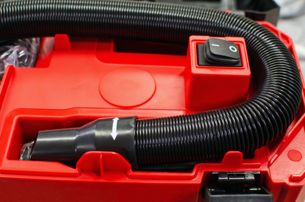 红色的工业真空吸尘器上有一根黑色的软管。工业真空软管。图片下载