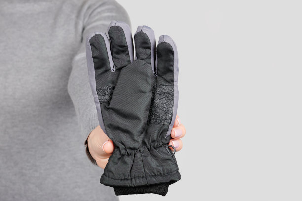 在灰色背景上戴上黑色冬季手套图片下载
