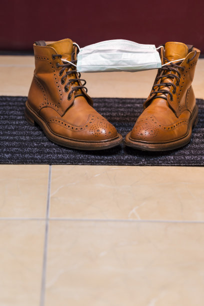 男式皮革鞣制布洛克高统靴覆盖面部医疗面具的门垫作为一个病毒保护标志。垂直的图像图片下载