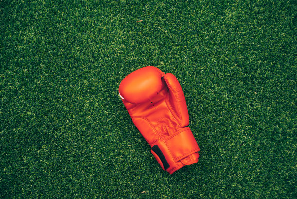 单只红色拳击手套在草地上的照片图片下载