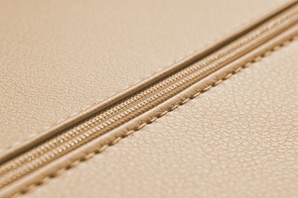 特写米色拉链上的皮革材料。服装和配饰背景。图片下载