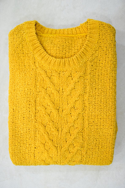 白色背景上折叠的黄色毛衣。轻便的衣服。图片下载