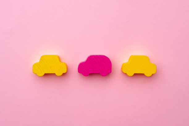 粉红色纸背景上木制的玩具汽车图片下载