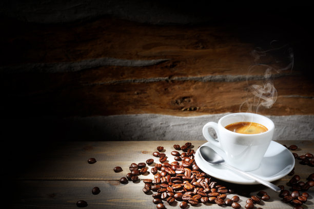 深色的木桌上放着热气腾腾的意式浓缩咖啡和咖啡豆，还有文字空间。图片下载