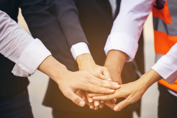 团结和成功的理念。工程师团队成员在集装箱堆场手拉手站立的底部视图。图片下载