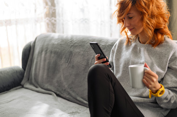 早上在家用智能手机喝咖啡的女人图片下载