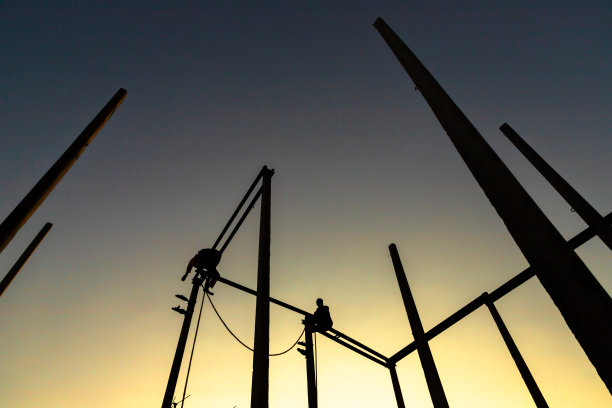 两个男人坐在电线杆上的剪影。图片下载