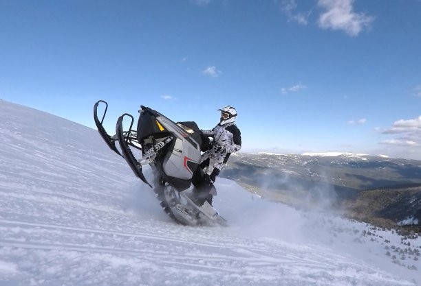冬天的雪地里，骑摩托的人在雪地里跳跃图片下载