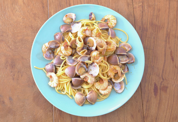 美味新鲜的自制海鲜意面，配上鱿鱼和虾，放在木桌上图片下载