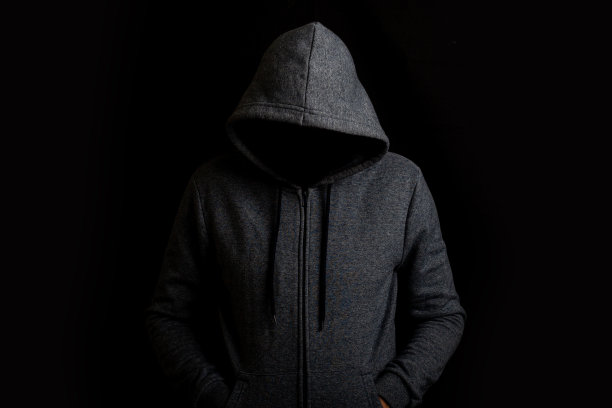 一个没有脸戴兜帽的人在黑暗的背景下图片下载