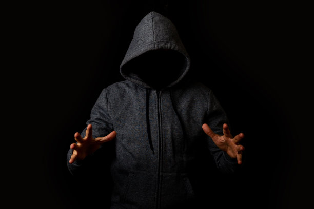 一个没有脸戴兜帽的人把手放在黑暗的背景上图片下载