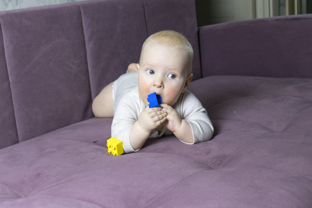 刚出生的白人男孩躺在沙发上玩玩具。过敏。发展。腹部。护理。孩子。图片下载