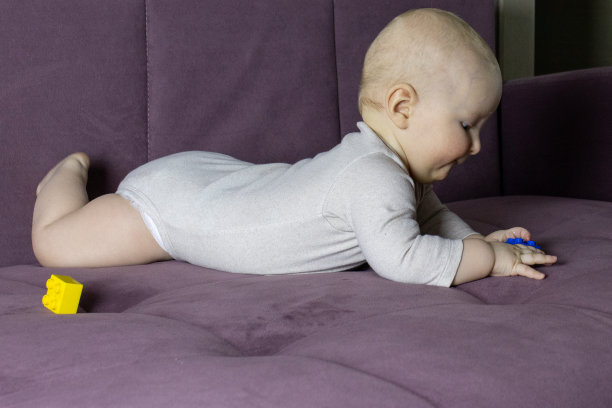 刚出生的白人男孩躺在沙发上玩玩具。过敏。发展。腹部。护理。孩子。图片下载