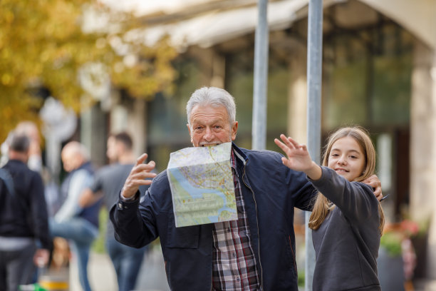 一位老人和他的孙女站在街上，手挥着手要叫出租车。图片下载