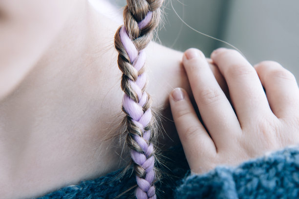 女孩穿着柔软温暖的蓝色针织毛衣，扎着一条粉红色的辫子图片下载