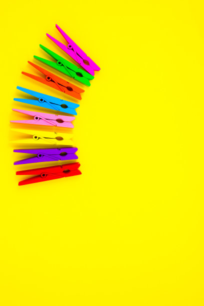 黄色背景上的彩色木衣夹。关闭，复制空间。极简主义，原创和创意的照片。是另一个。个性的概念。垂直墙纸智能手机。图片下载