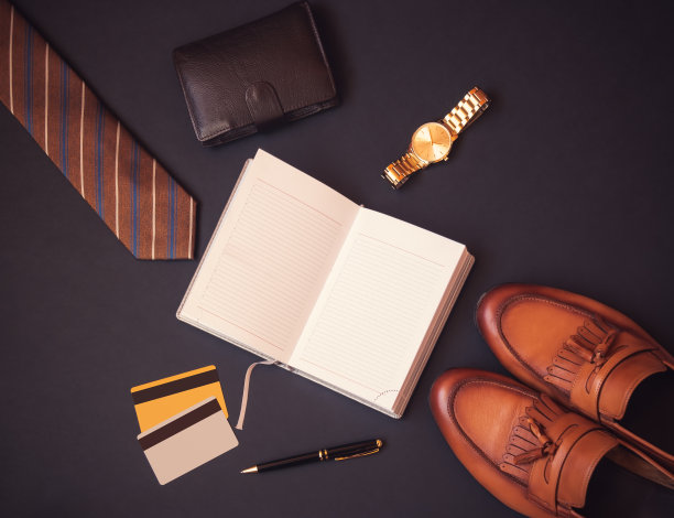 打开日记本，领带，钱包，手表，信用卡，钢笔和时尚的鞋子在黑暗的背景。图片下载