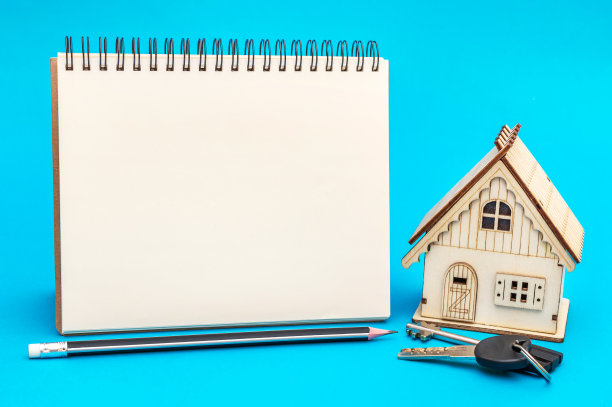 空白记事本与模型的房子在蓝色的背景。图片下载