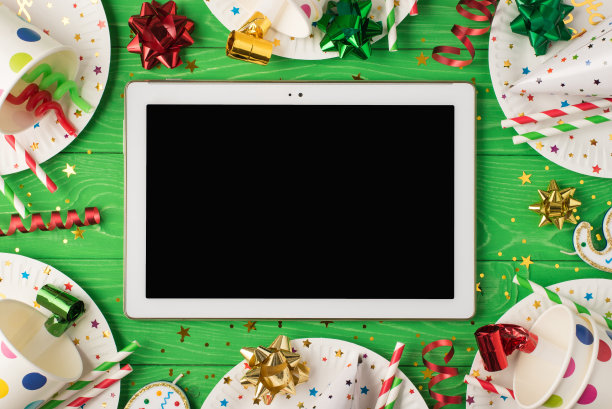 生日聚会作文的顶视图照片平板电脑在中间与copyspace丝带星星蜡烛管子草帽亮片纸杯盘子在孤立的绿色木制桌子的背景图片下载