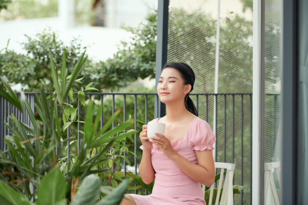 年轻的亚洲女性在阳台上喝咖啡图片下载