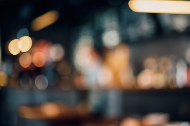 咖啡店用散景灯光模糊背景。酒吧和桌子模糊的轮廓，昏暗的灯光图片下载