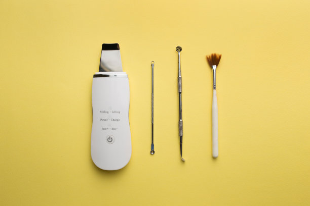 超声波清洗机，化妆品脱皮刷一匙放在黄色背景上。平铺，美容的概念和工具图片下载