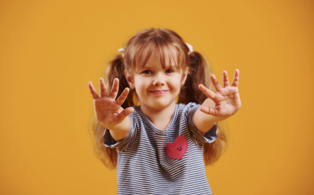 可爱的小女孩穿着休闲的衣服在黄色的背景下的工作室图片下载