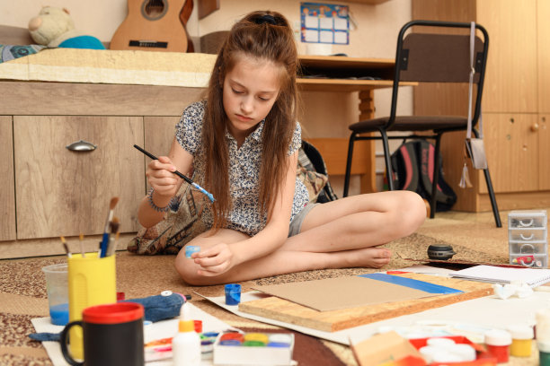 女孩在家里画画，进行艺术创作，用纸、颜料和画笔制作创造性的艺术品图片下载